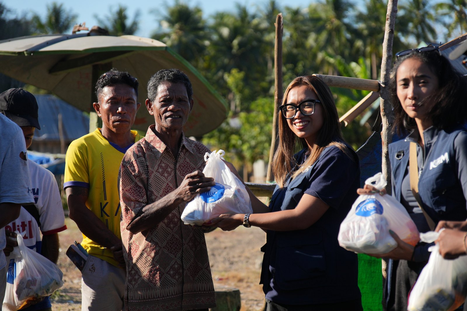 A KGM ambassador handing supplies to a man in Flores