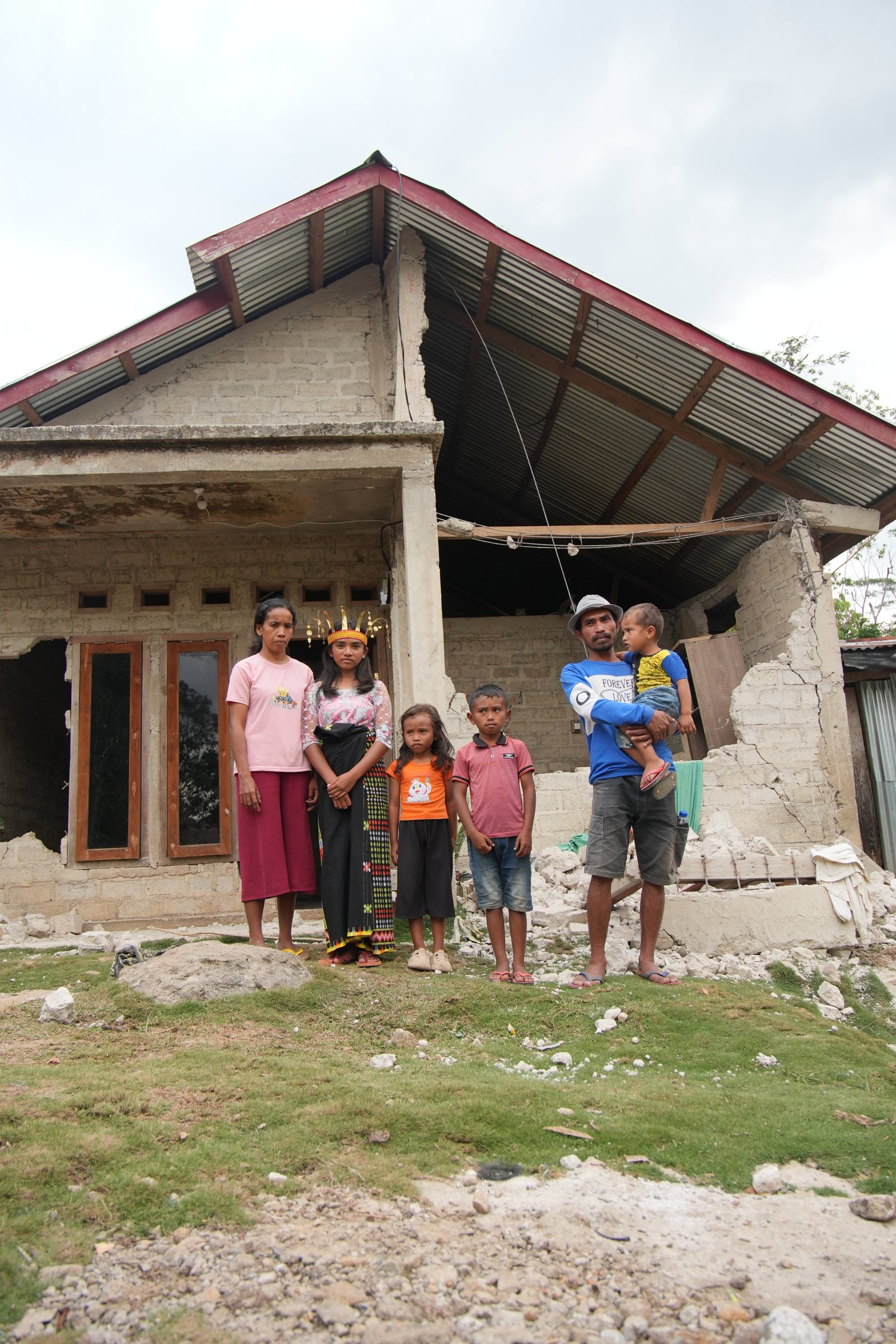 Prili's family in front of their damaged home